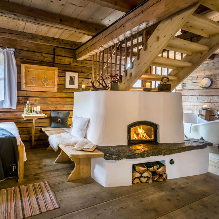 Urige Hüttenatmosphäre am Kamin im Chalet | Bergdorf PRIESTEREGG Gemütlichkeit und Entspannung mit Kamin und Badewanne im Chalet in Leogang