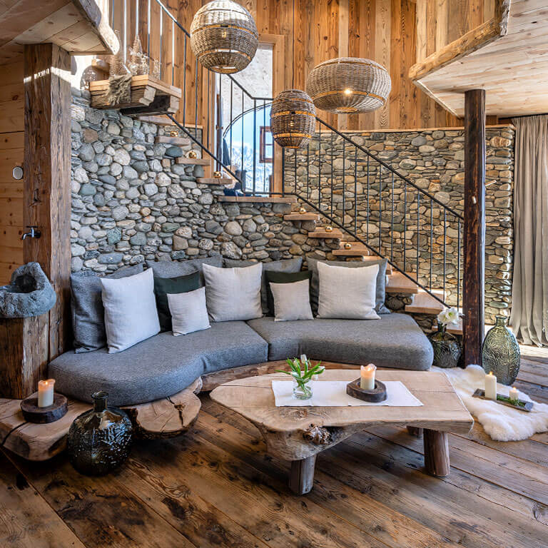 Gemütlichkeit und Komfort in der Wilderer Villa | Chalets und Villen im PRIESTEREGG Wohnzimmer mit Naturmaterialien Holz und Stein in der Wilderer Villa im Priesteregg Leogang Oesterreich